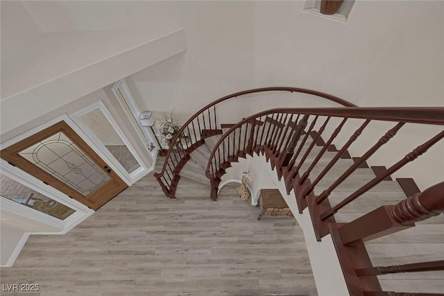 staircase with arched walkways and wood finished floors