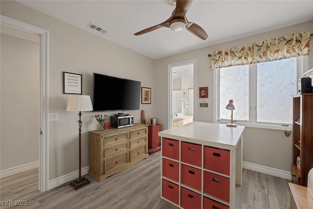 interior space with ceiling fan, connected bathroom, visible vents, baseboards, and light wood-style floors