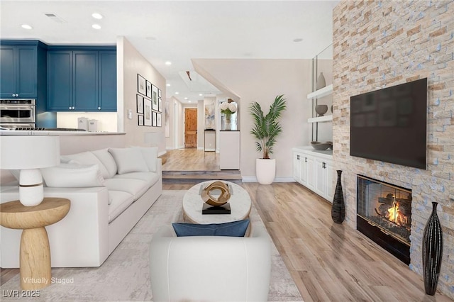 living room featuring a fireplace, recessed lighting, visible vents, light wood-style flooring, and baseboards