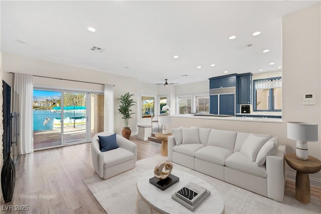 living room featuring light wood-style flooring, visible vents, baseboards, and recessed lighting