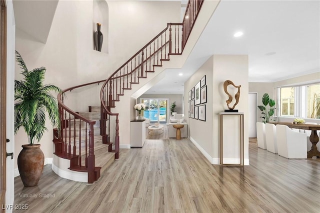 entryway featuring light wood-style flooring, stairs, baseboards, and ornamental molding