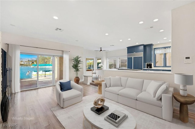 living room featuring a wealth of natural light, visible vents, light wood finished floors, and recessed lighting