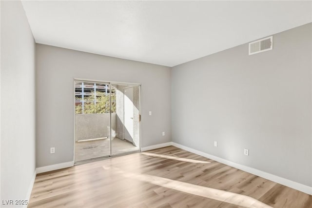 empty room with baseboards, visible vents, and wood finished floors