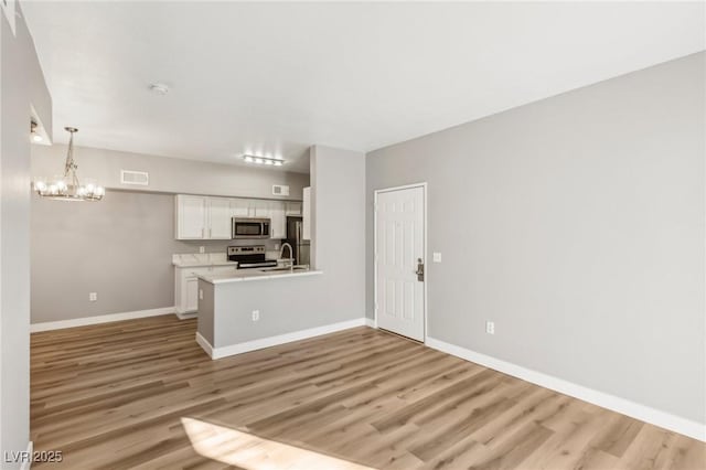 kitchen with stainless steel appliances, light wood finished floors, visible vents, and white cabinetry