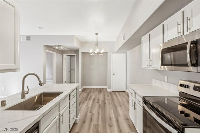 kitchen with white cabinets, appliances with stainless steel finishes, light stone countertops, and sink