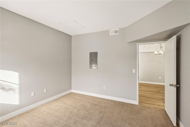 carpeted empty room with baseboards, electric panel, visible vents, and a notable chandelier