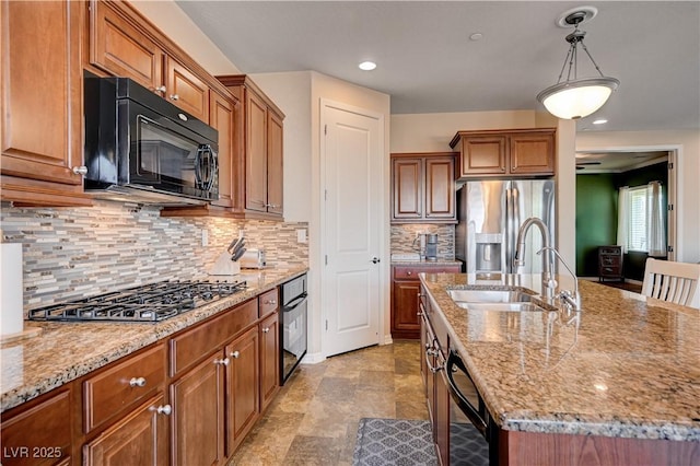 kitchen with tasteful backsplash, sink, black appliances, decorative light fixtures, and an island with sink