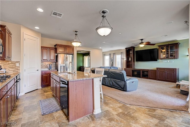 kitchen featuring sink, an island with sink, decorative light fixtures, a breakfast bar area, and appliances with stainless steel finishes