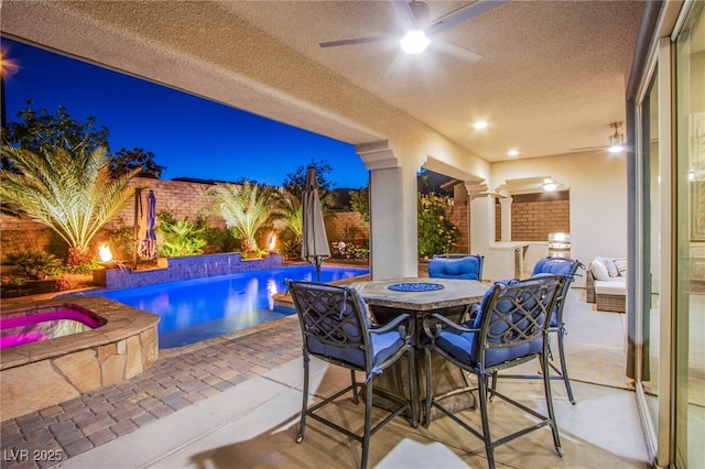 view of patio featuring ceiling fan and a pool with hot tub