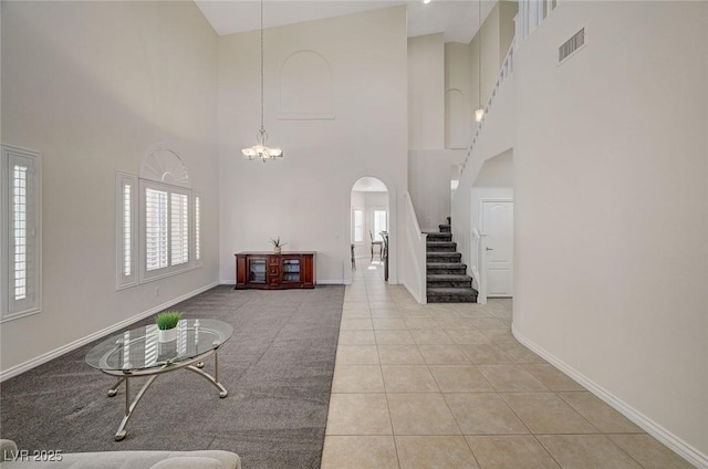 interior space with a wealth of natural light, light tile patterned floors, a high ceiling, and a chandelier