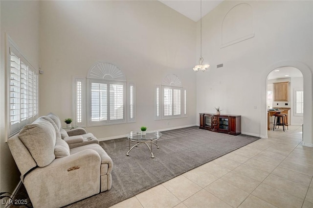 tiled living room with a towering ceiling and a notable chandelier