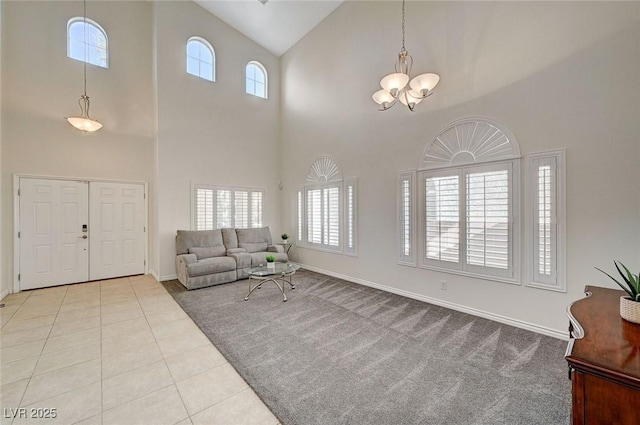 tiled living room featuring plenty of natural light, a towering ceiling, and a notable chandelier