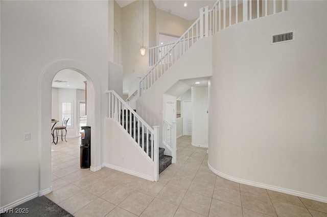 stairs featuring tile patterned flooring and a towering ceiling