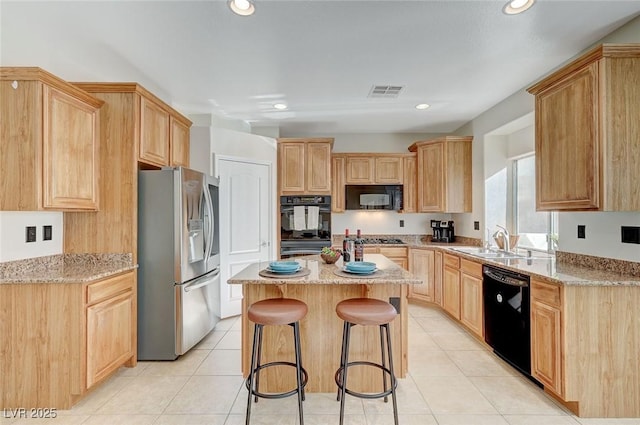 kitchen featuring a breakfast bar, light stone counters, sink, and black appliances