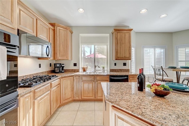 kitchen with light stone counters, stainless steel appliances, sink, light brown cabinets, and light tile patterned flooring