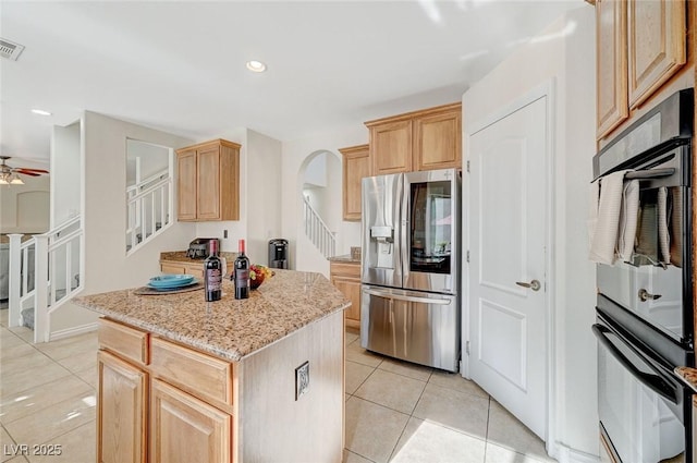 kitchen with stainless steel refrigerator with ice dispenser, light tile patterned floors, light stone countertops, light brown cabinetry, and a kitchen island