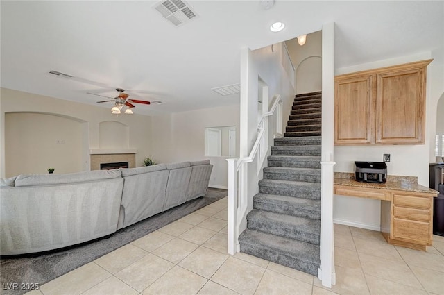 living room featuring ceiling fan, light tile patterned flooring, and built in desk