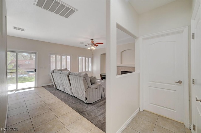 tiled living room featuring ceiling fan and a fireplace