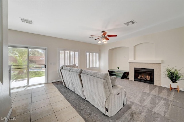 tiled living room featuring a tile fireplace and ceiling fan