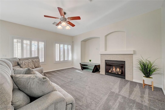 carpeted living room featuring a tile fireplace and ceiling fan