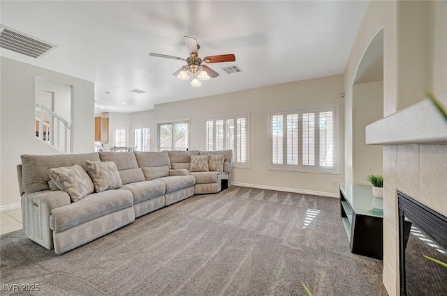 carpeted living room featuring ceiling fan and a tiled fireplace