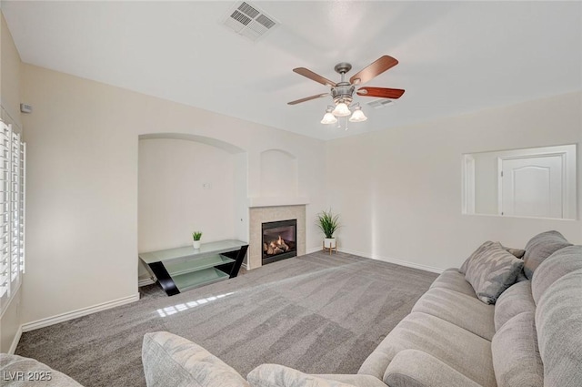 living room featuring carpet, ceiling fan, and a tiled fireplace