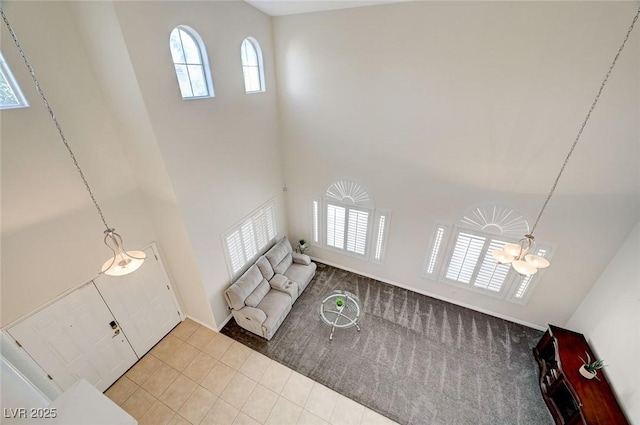 living room featuring a towering ceiling, an inviting chandelier, and light tile patterned flooring