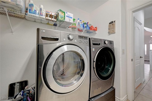 laundry area featuring washing machine and clothes dryer and light tile patterned floors