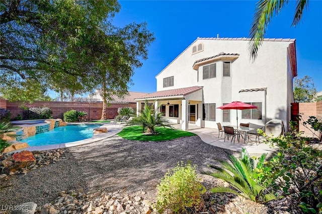 rear view of property with ceiling fan, a pool with hot tub, and a patio area