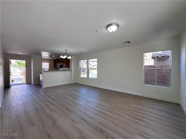 unfurnished living room with light hardwood / wood-style flooring and an inviting chandelier