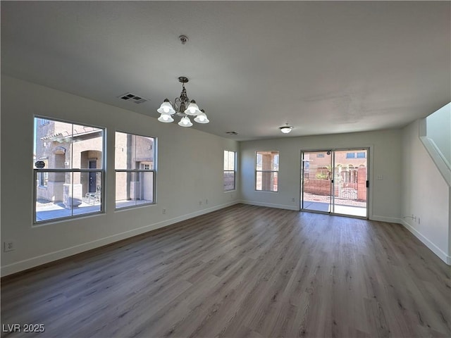 unfurnished room featuring wood-type flooring and a notable chandelier