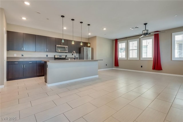 kitchen featuring pendant lighting, a kitchen island with sink, sink, appliances with stainless steel finishes, and dark brown cabinetry