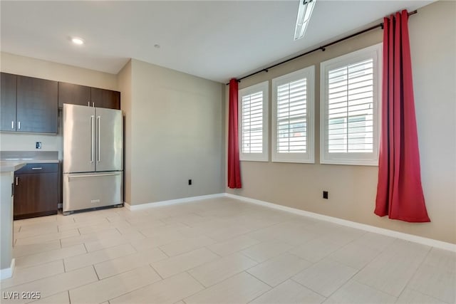 kitchen featuring stainless steel fridge and dark brown cabinets