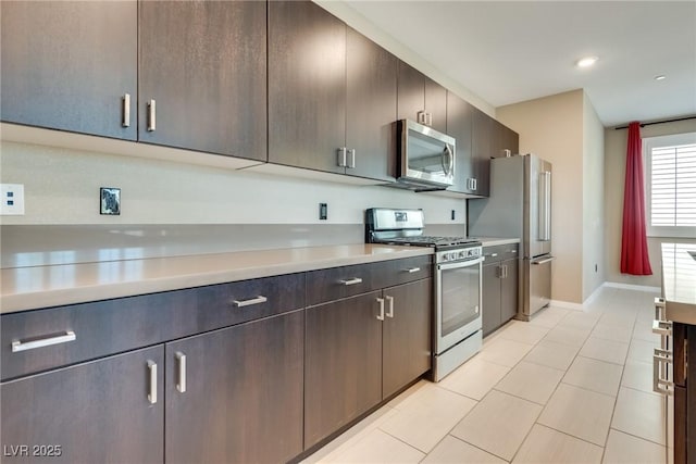 kitchen with dark brown cabinets, light tile patterned floors, and stainless steel appliances