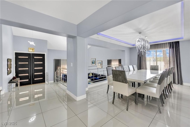 tiled dining area featuring a tray ceiling and a chandelier