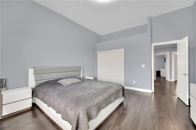 bedroom featuring dark hardwood / wood-style floors, lofted ceiling, and a closet