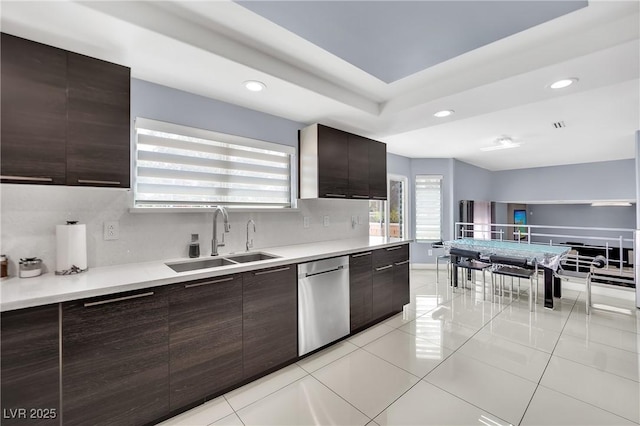 kitchen with dark brown cabinets, light tile patterned floors, stainless steel dishwasher, and sink