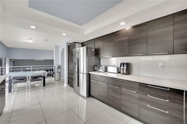 kitchen with stainless steel fridge with ice dispenser, light tile patterned flooring, and dark brown cabinetry