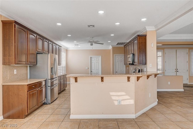 kitchen featuring a breakfast bar, backsplash, ornamental molding, appliances with stainless steel finishes, and kitchen peninsula