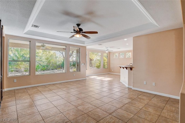 empty room with light tile patterned floors, a raised ceiling, and crown molding