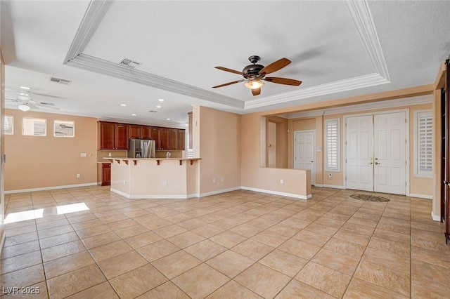 unfurnished living room featuring a tray ceiling, ceiling fan, light tile patterned floors, and ornamental molding