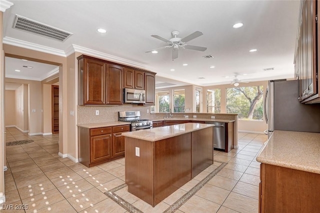 kitchen with a healthy amount of sunlight, light tile patterned flooring, crown molding, a kitchen island, and appliances with stainless steel finishes