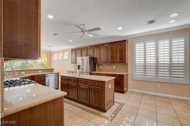 kitchen with sink, ceiling fan, light tile patterned floors, ornamental molding, and appliances with stainless steel finishes