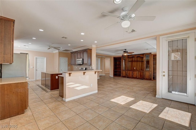 kitchen with a breakfast bar area, a center island, ornamental molding, and appliances with stainless steel finishes