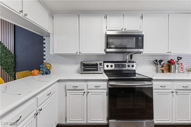 kitchen with stainless steel appliances, white cabinets, light stone counters, and tasteful backsplash