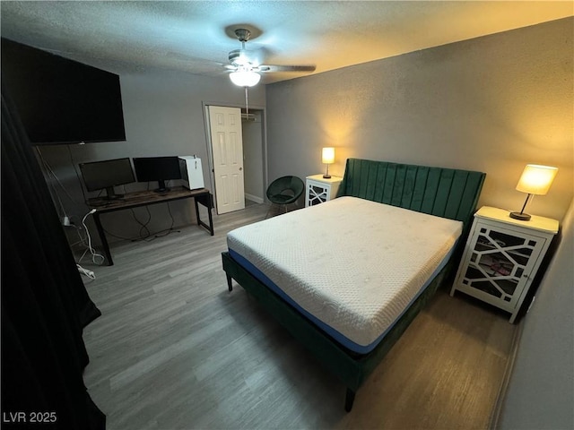 bedroom with hardwood / wood-style floors, ceiling fan, and a textured ceiling