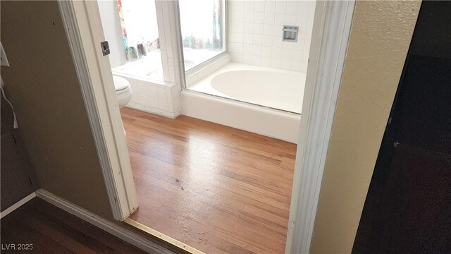 bathroom with a bathtub, wood-type flooring, and toilet