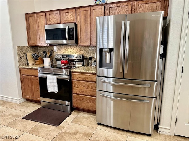 kitchen with light stone countertops, light tile patterned floors, stainless steel appliances, and tasteful backsplash