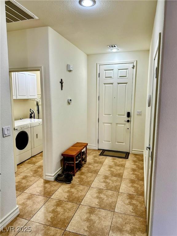 foyer entrance featuring washing machine and dryer and light tile patterned flooring