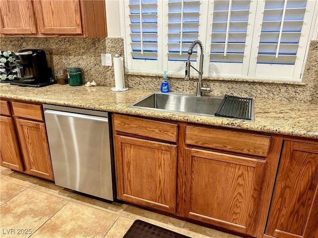 kitchen featuring light stone countertops, dishwasher, sink, decorative backsplash, and light tile patterned floors